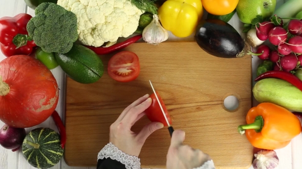 Woman Cuts Red Tomato Among The Fresh Vegetables