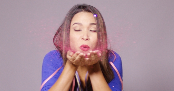 Fun Young Woman Blowing a Spray Of Confetti alt