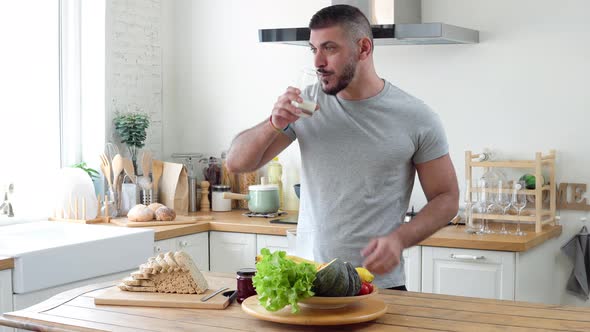 Healthy muscular caucasian man having breakfast and talking on cellphone in the morning at kitchen
