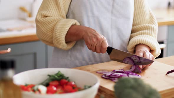 Hands of Woman Chopping Red Onion on Kitchen
