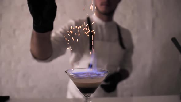 Bartender Sprinkling Cinnamon Powder Over Irish Cream Cocktail on Fire alt