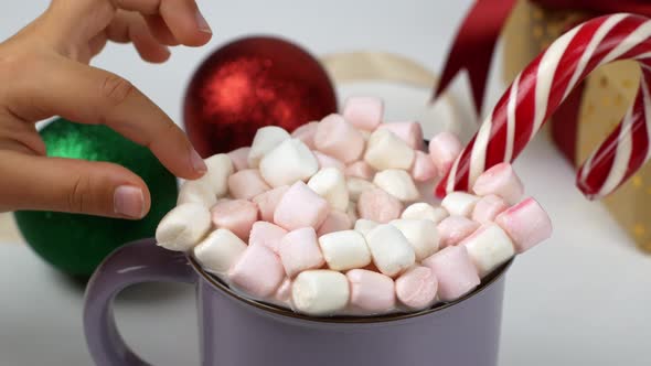 Purple cocoa mug with wrappers, caramel cane and Christmas presents on a light background. alt