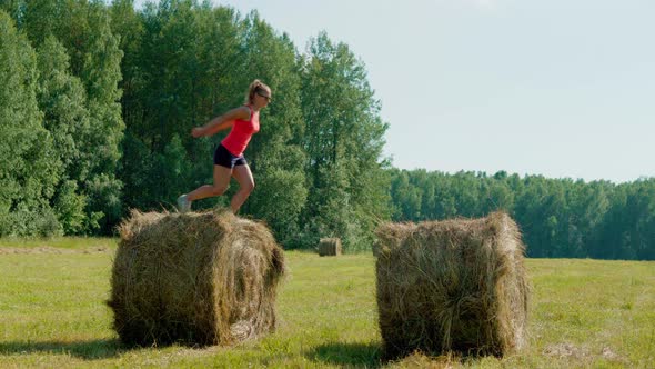 Elegant Girl in the Summer in the Field Jumps From Haystack to Haystack