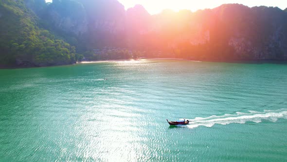 4K aerial view over a ship sailing at sea, mountains in the background. alt