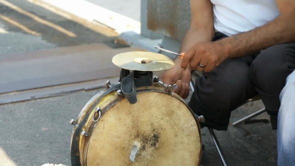 A Tanned Man Playing On The Old Drum Outdoors