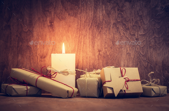 Chistmas presents, gifts with a candle glowing on wooden wall background. - Stock Photo - Images