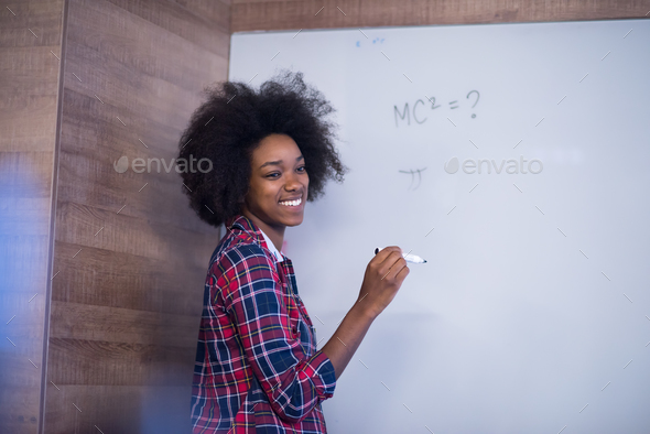 African American woman writing on a chalkboard in a modern offic