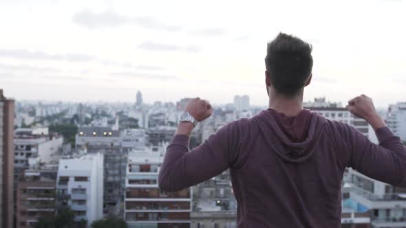 Rear view of man stretching his hands while looking at cityscape