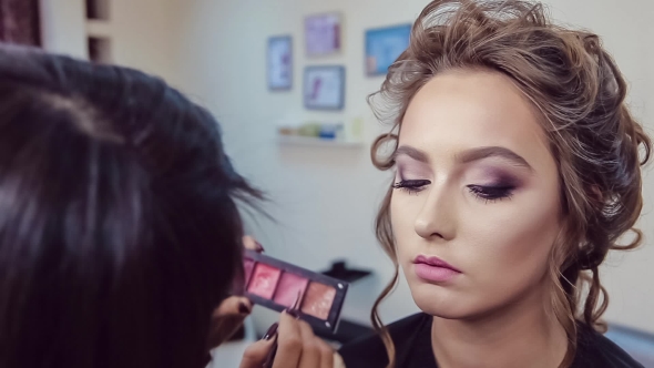 Make Up Artist Doing Professional Makeup Of Young Woman In Beauty Studio