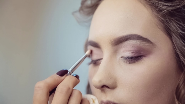 Make Up Artist Doing Professional Eye Makeup Of Young Woman