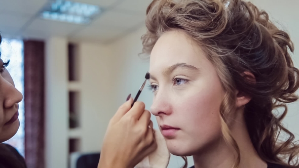 Make Up Artist Doing Professional Makeup Of Young Woman In Beauty Studio