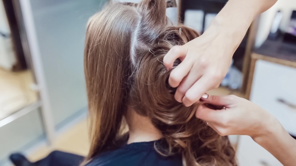 Hair Stylist Makes Professional Hairstyle Of Young Woman In Beauty Studio