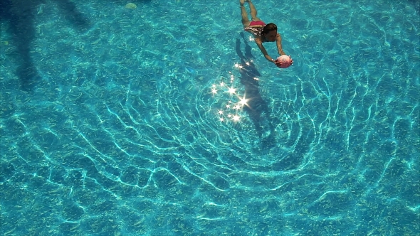 Young Woman Playing With Ball On Swimming Pool