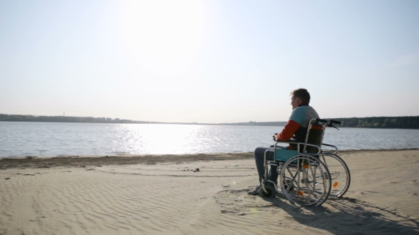 Man Sitting In a Wheelchair On The Shore