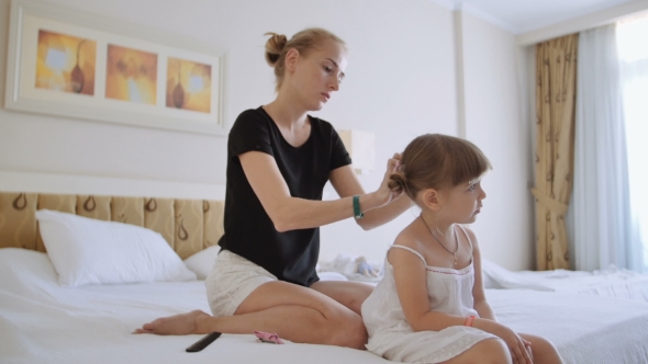 Mom Makes Hairstyle For a Little Girl.