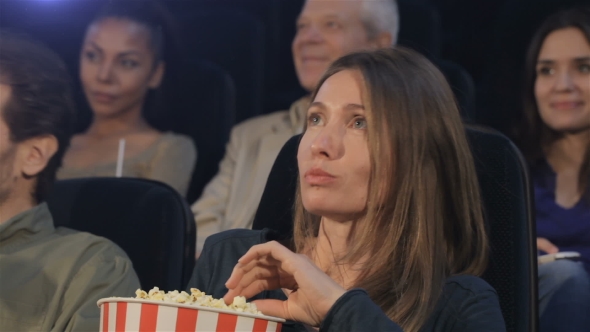 Woman Puts Popcorn Into Her Mouth At The Movie Theater alt