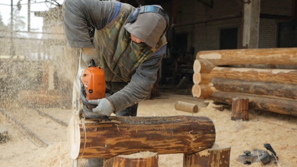 Builder Handles Wooden Timber Chainsaw. Against The Background Is Part Of The Future Of The House