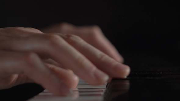 Hands Of a Woman Playing The Piano On Black Background