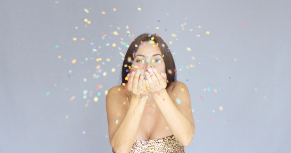 Young Woman Blowing Colorful New Year Confetti alt