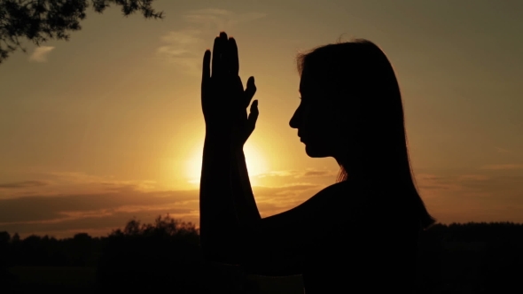 Young Woman Praying In The Forest At Sunset