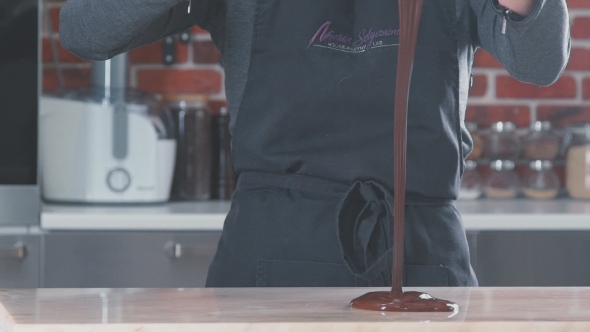 Confectioner And Pouring Hot Melted Chocolate On a Table.