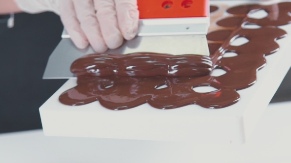 Making Chocolates Candies. Removing Surplus Chocolate From The Mold.