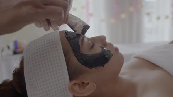 Young beautiful woman makes charcoal spa therapy alt