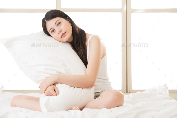 beautiful asian woman feel sleepy and holding pillow in morning