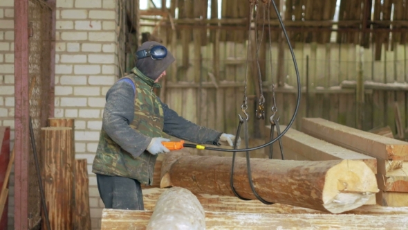Builder Raises Wooden Timber With Overhead Winch Crane. A Man Holds a Log And Transfer It