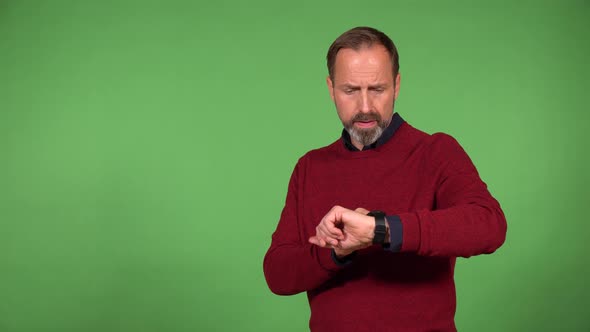 A Middleaged Handsome Caucasian Man Works on a Smartwatch  Green Screen Background