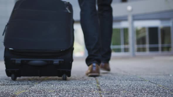 Low section of african american businessman walking with suitcase in street alt