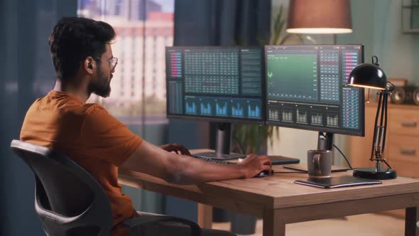 Indian Man Analyzing Stock Graphs on Computer alt