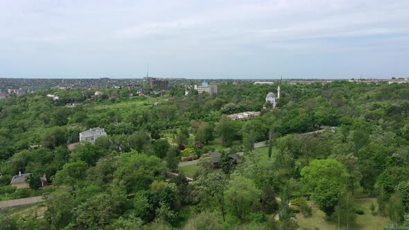 A bird's eye view of the city garden. Among the trees you can see a mosque alt