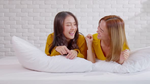 Beautiful two female LGBT lesbian embracing and looking together with love and romance on bed alt