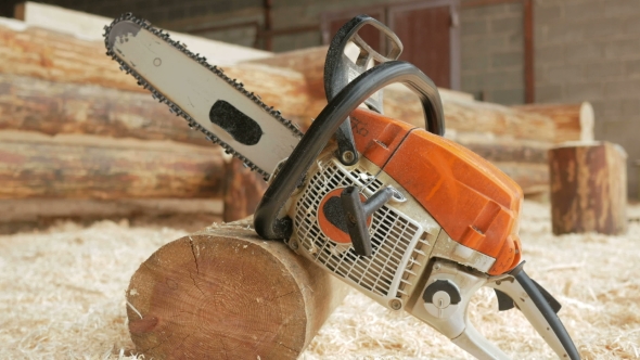 Chainsaw Builder At The Site Of Construction Of a Wooden House. Many Sawdust And a Part Of The