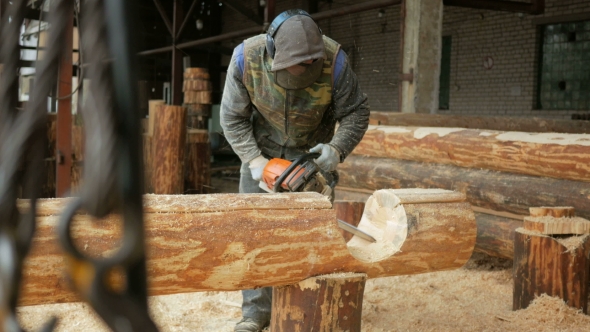 Man Cuts Wood Chainsaw For Future Home. Protective Face Mask On The Face Of The Builder
