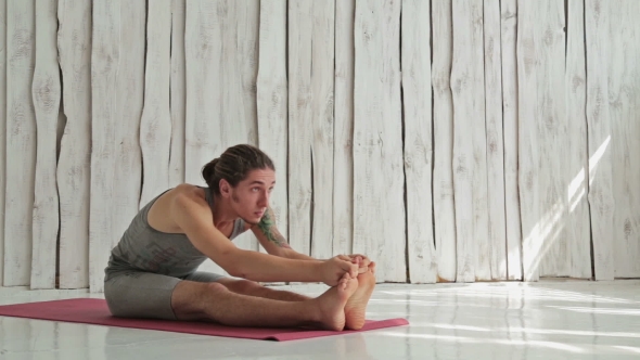 Young Sporty Man Practicing Yoga In Fitness Studio