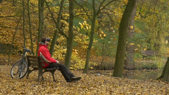 Man in 360Vr Glasses on Bench Leaned Back in Park alt