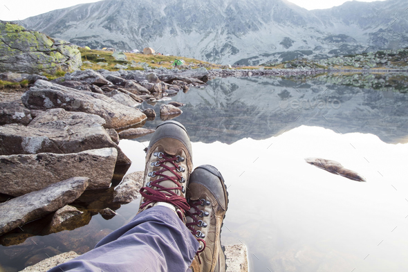 Hiking.Woman legs with boots and mountain lake view