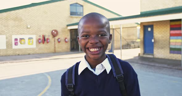 Portrait of a young schoolboy smiling in playground alt