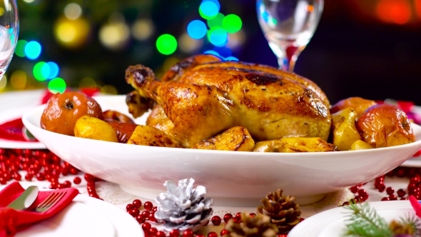 Roasted Chicken On Christmas Table In Front Of Fireplace And Tree With Lights