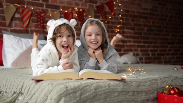 Cute Smiling Sister And Brother Reading a Book And Laughing At The Home In a Christmas Time. They alt