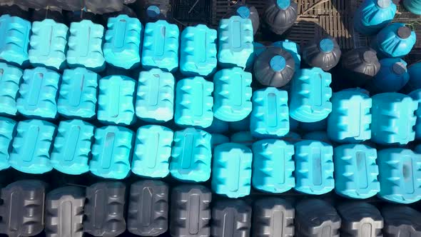 Aerial View of Blue and Black Plastics Barrels Tanks Open-air Warehouse alt