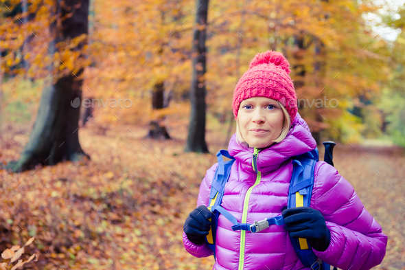 Hiking woman with backpack looking at camera in inspiring autumn - Stock Photo - Images