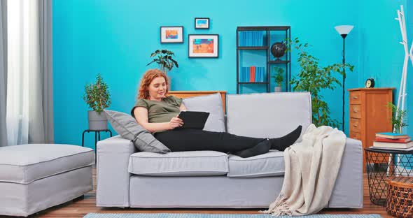 Woman Relaxes After Hard Day on Sofa in Living Room Legs Lined Along the Couch alt