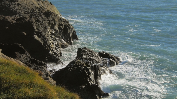 Beautiful Blue Waves Of Atlantic Ocean Are Breaking Of Black Basalt Cliffs In Sunny Day