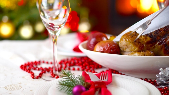 Roasted Chicken On Christmas Table In Front Of Fireplace And Tree With Lights