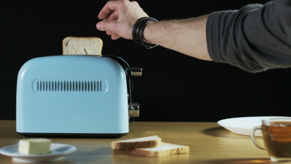 Man Puts Two Loaves Of Bread Into An Electric Toaster alt