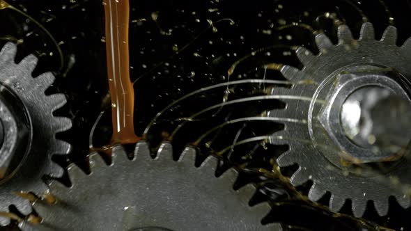Super Slow Motion Detail Shot of Gear Mechanism and Oil on Dark Background at 1000 Fps alt
