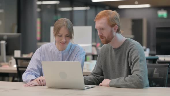 Young Man and Woman Discussing Work on Laptop alt
